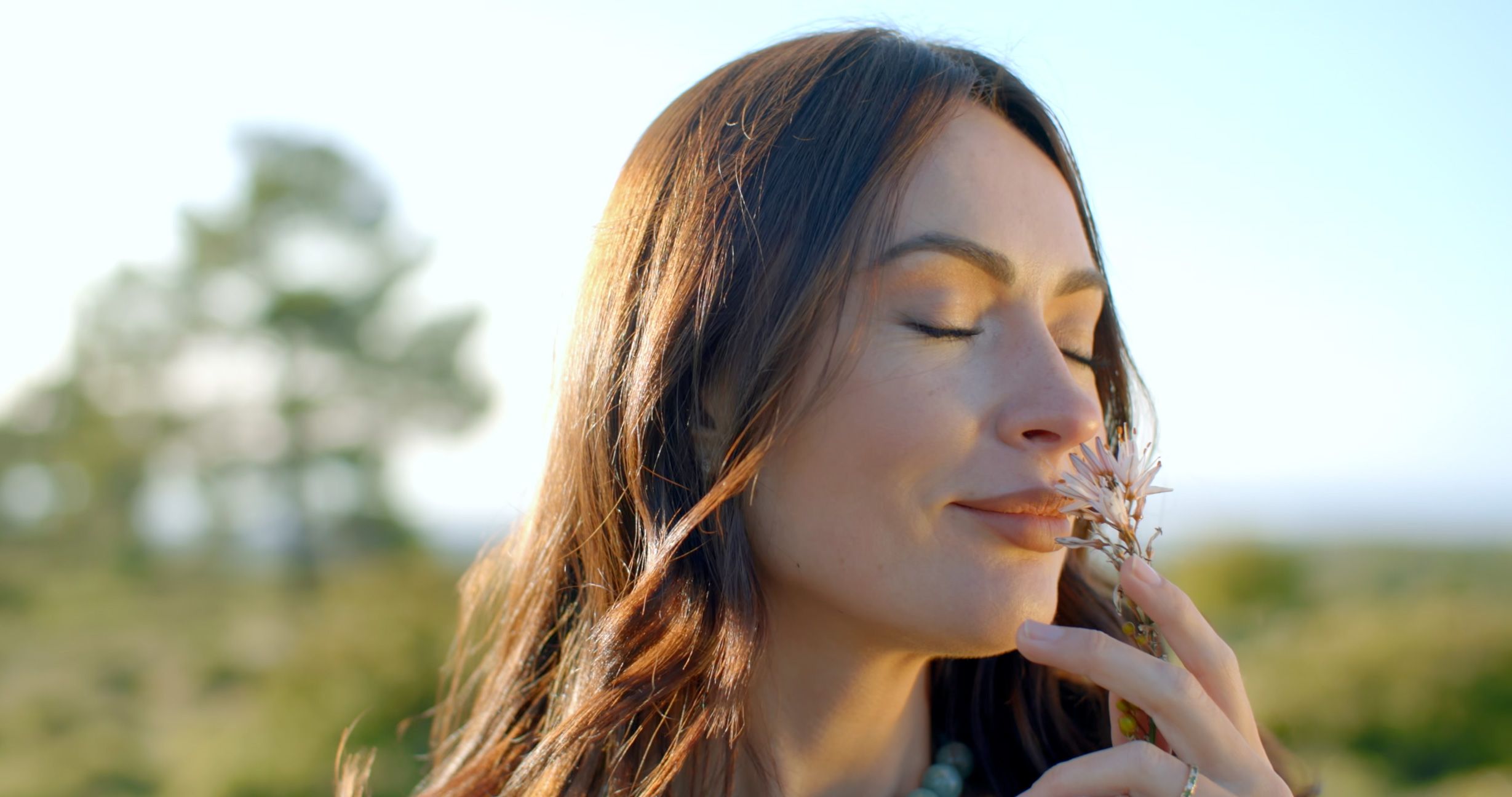 Woman smelling a wildflower in the warm evening light