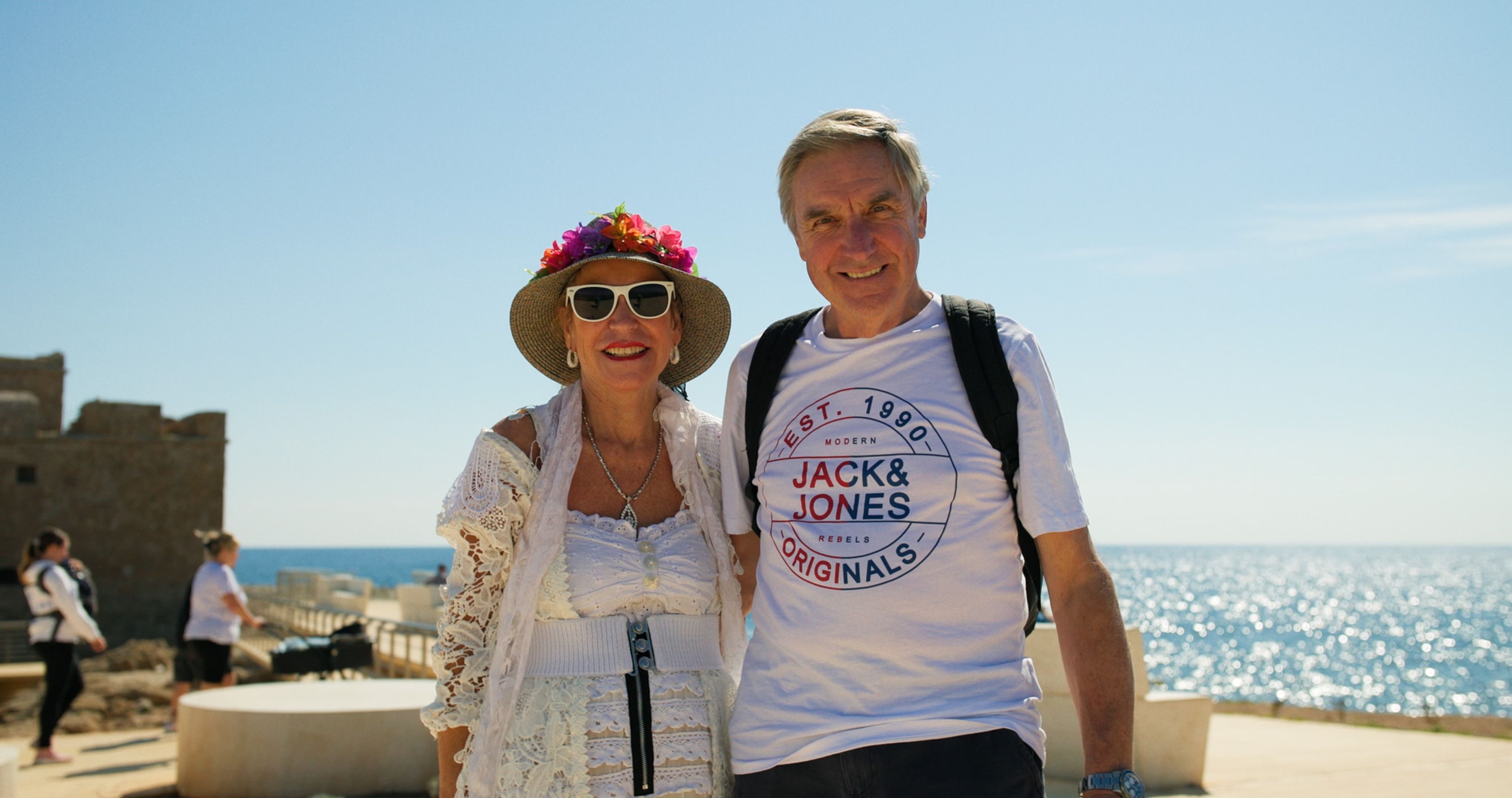Two visitors smiling by the Mediterranean Sea in Cyprus.