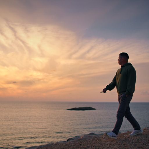 Andrey Iavita walking along the Cyprus coast at sunset with the Discover Cyprus title.