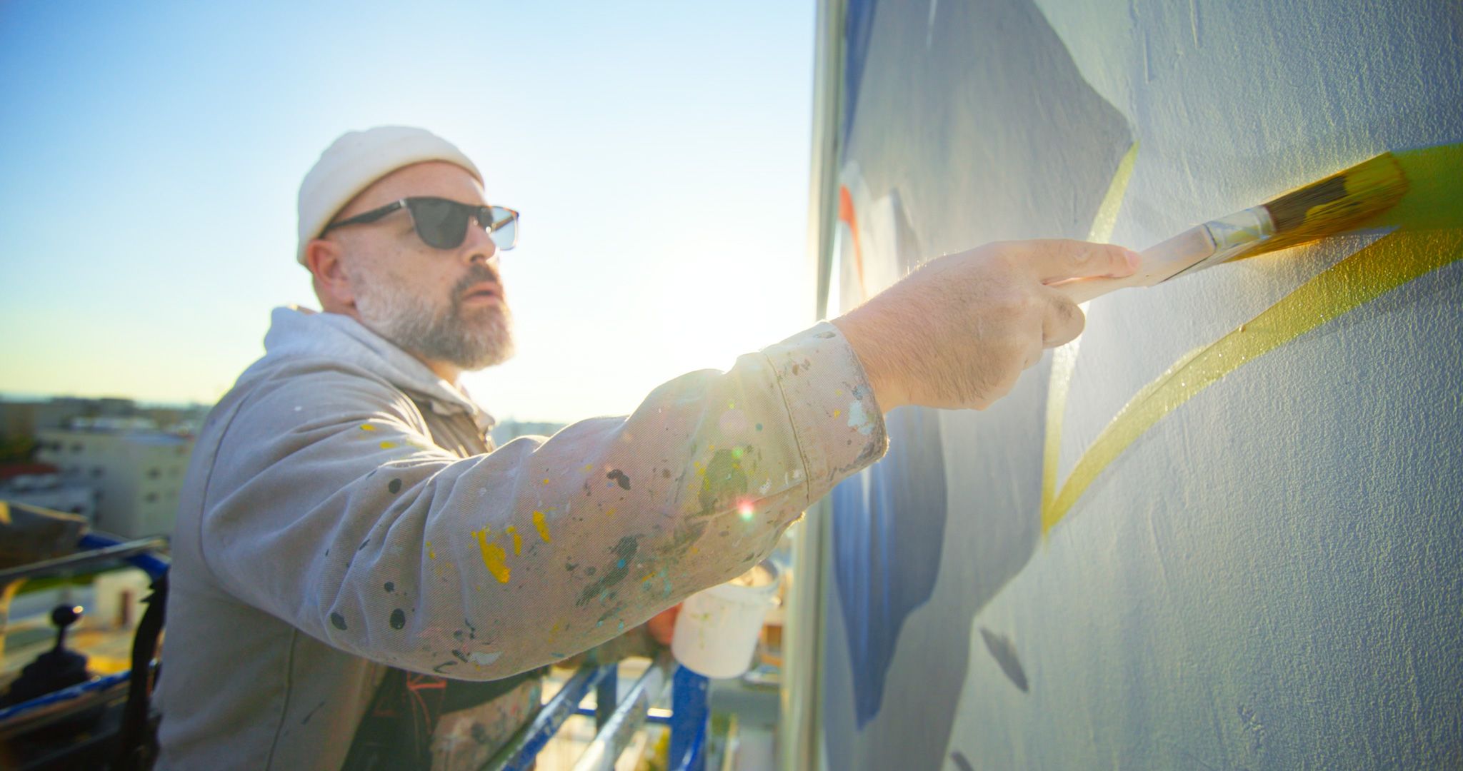 Italian artist Millo painting a large mural on an Art Square residential building.