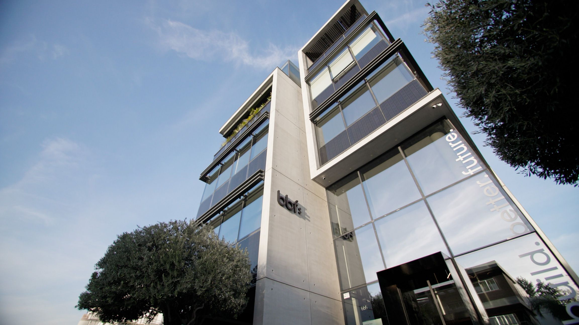 Low-angle exterior view of a modern bbf: office building with the company logo.