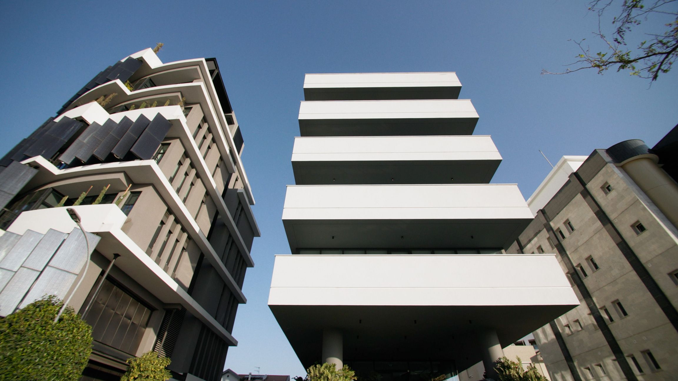 Low-angle view of contemporary commercial buildings with geometric balconies against a blue sky.