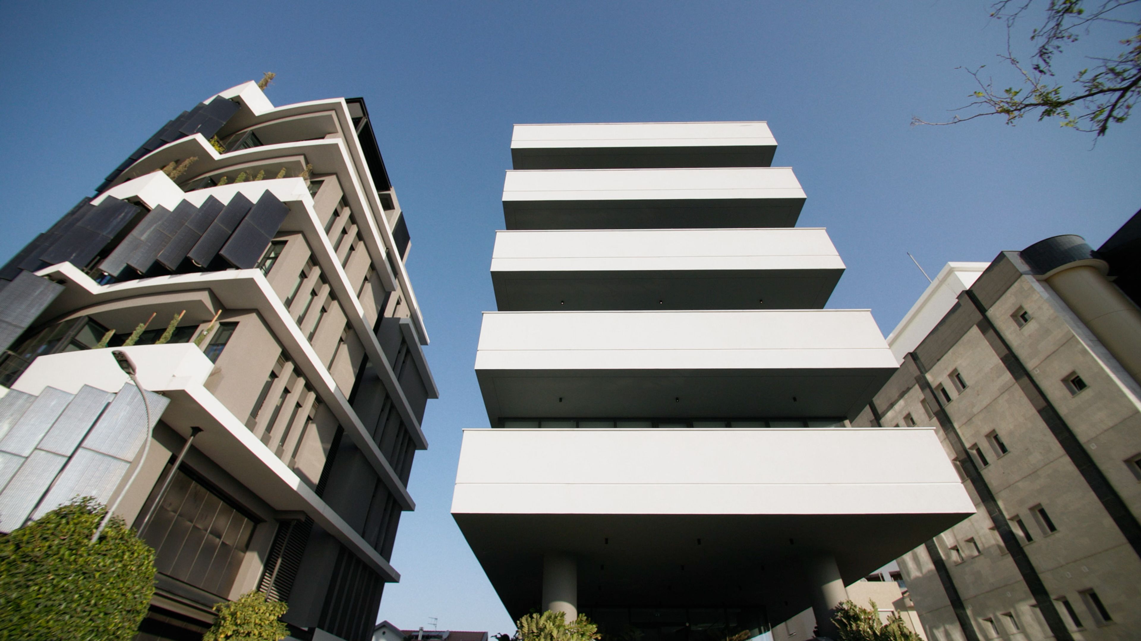 Low-angle view of contemporary commercial buildings with geometric balconies against a blue sky.