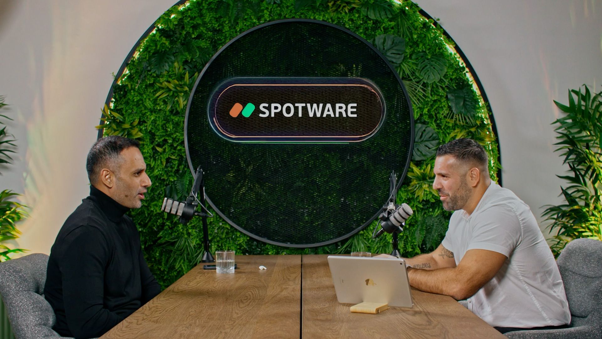 Spotware podcast host and guest seated across a table beneath the Spotware logo.