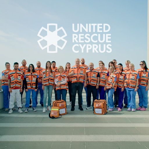 United Rescue Cyprus volunteers in orange emergency vests standing together with medical response kits.