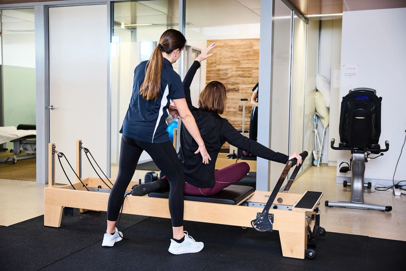 Bright Pilates studio with reformers and a physiotherapist working with a client