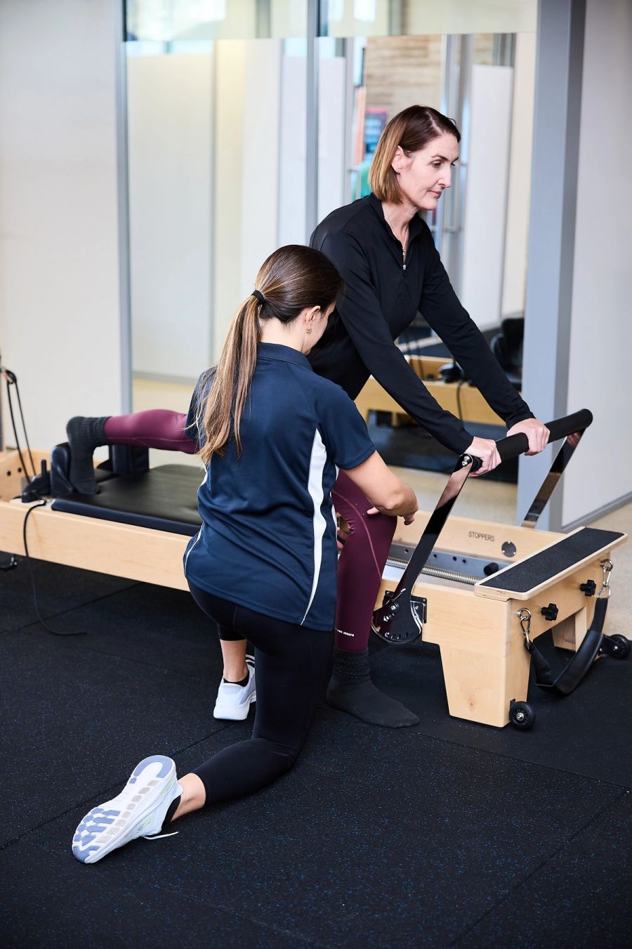 Physiotherapist guiding a client through a Clinical Pilates exercise on the reformer