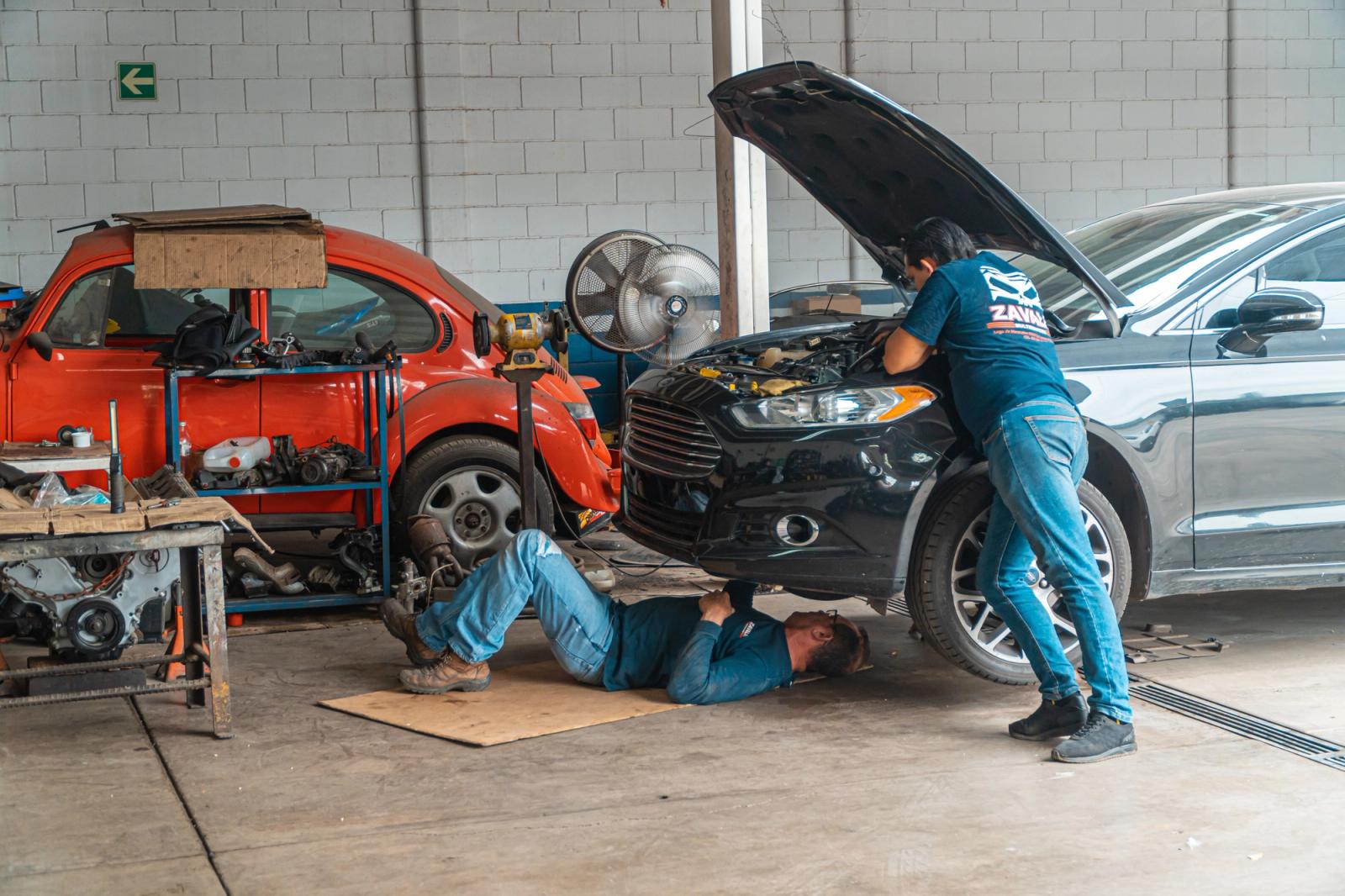 Mechanics working together around vehicles in an automotive workshop