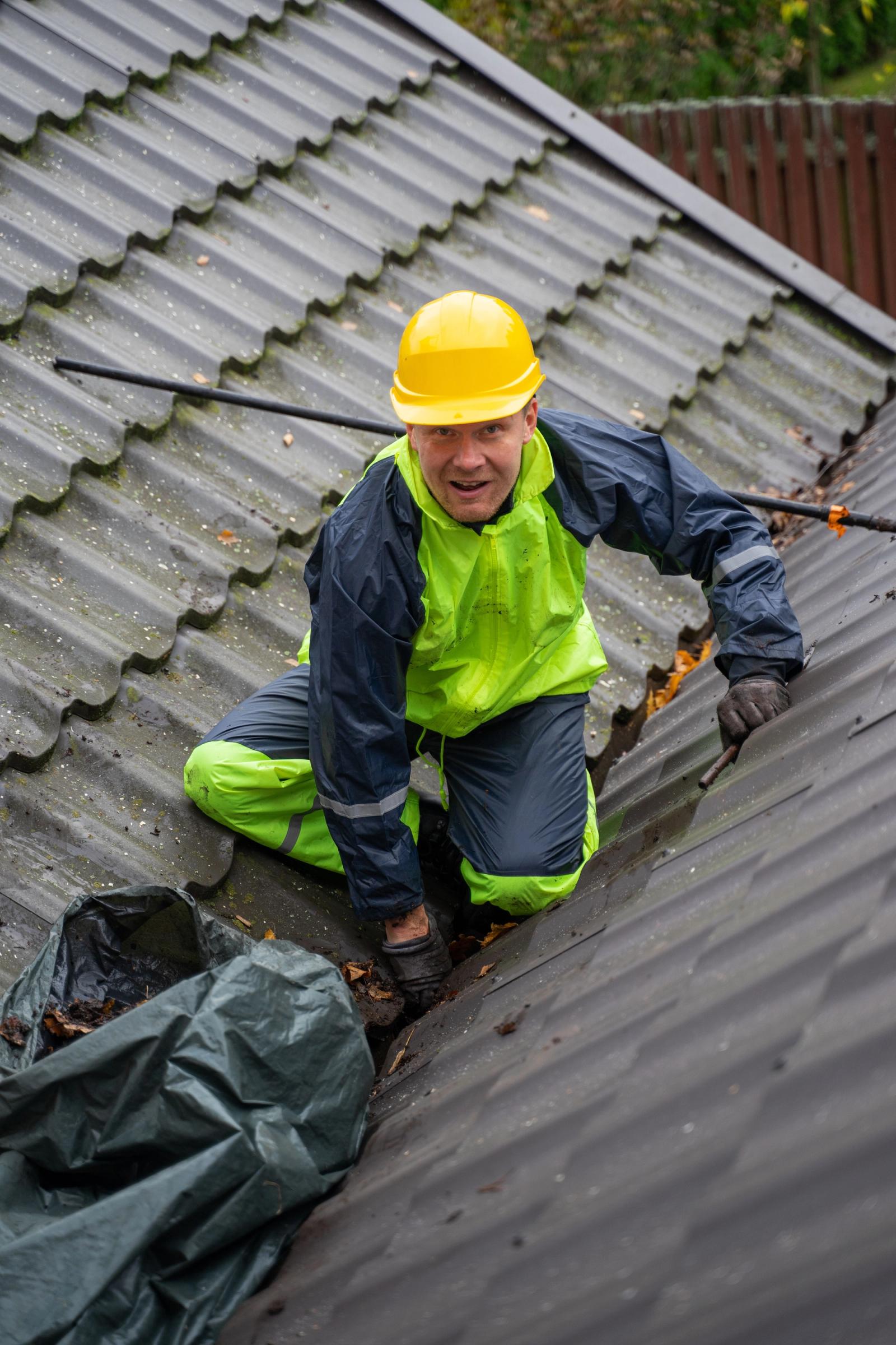 Roofing worker in safety gear standing on a residential roof