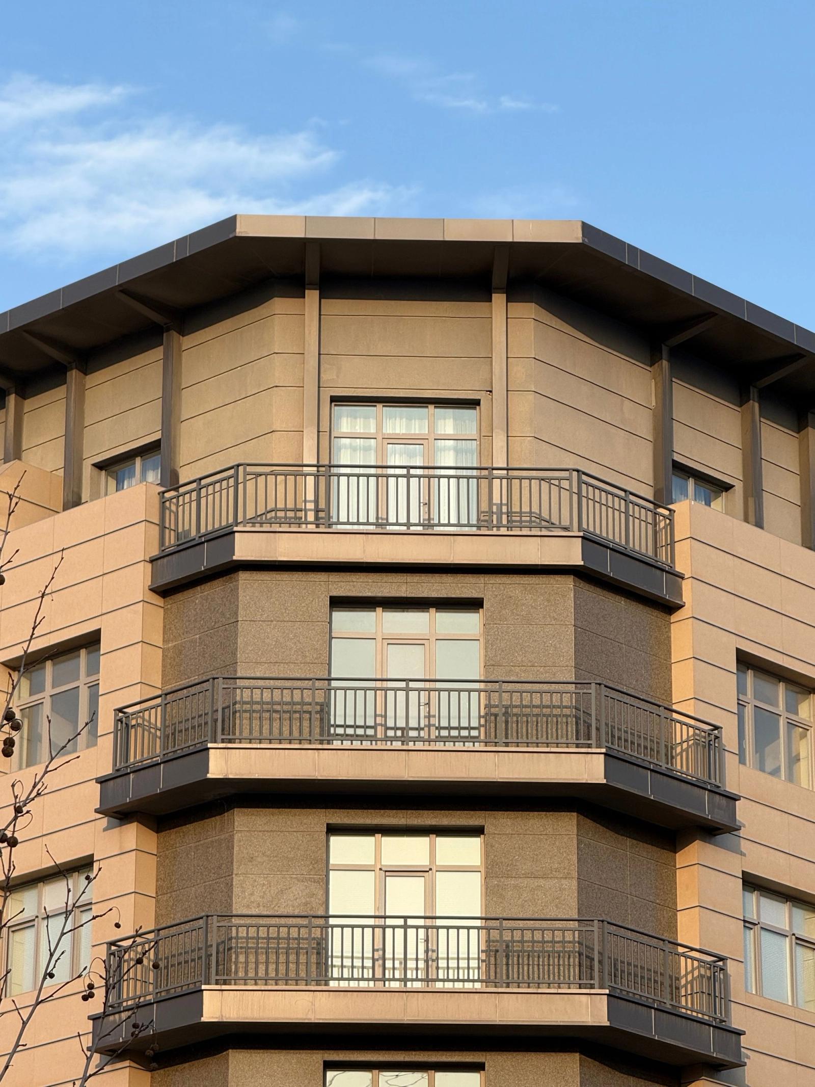 Modern apartment building with balconies and large windows under a clear blue sky