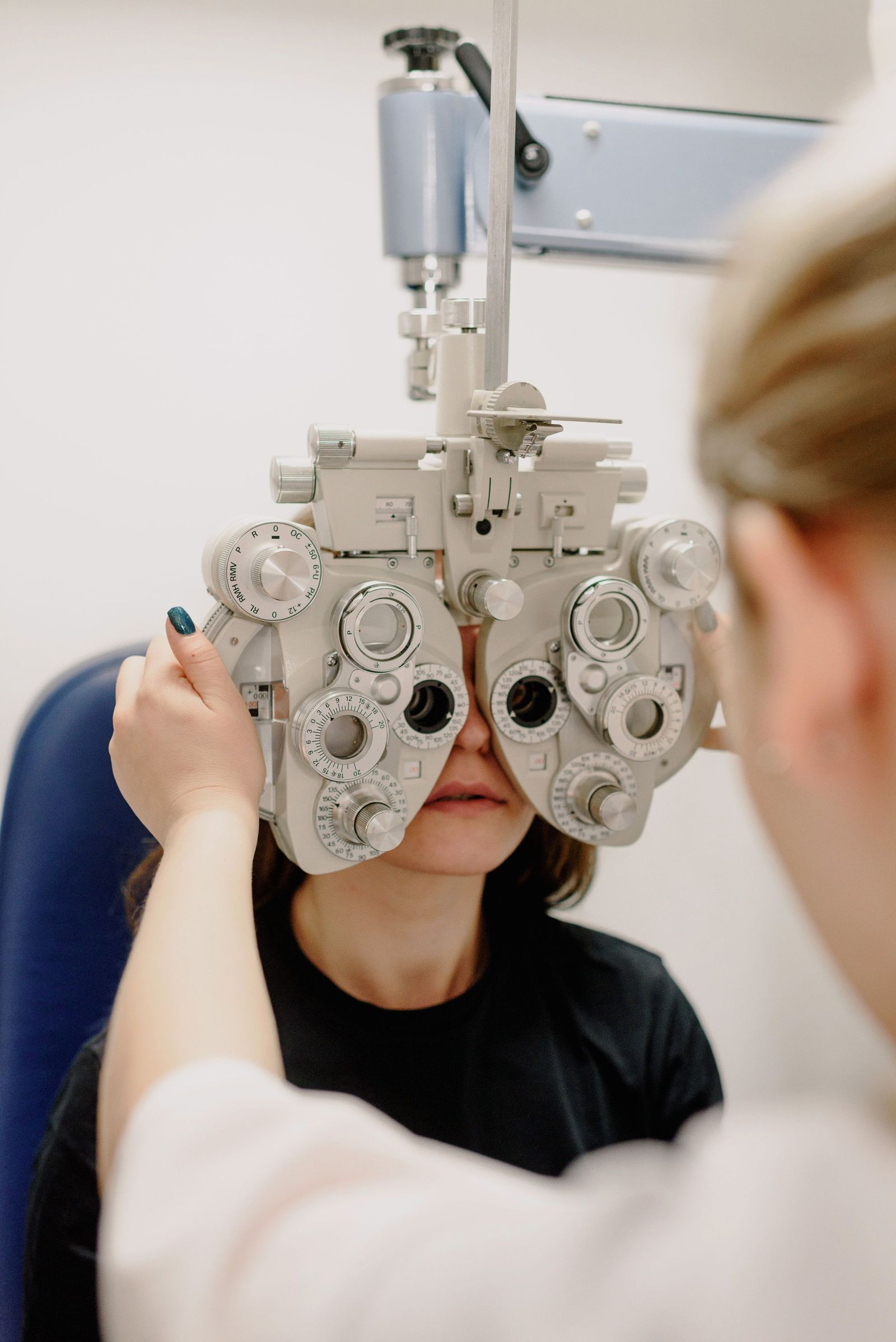Eye-care professional adjusting a phoropter during a patient's vision examination