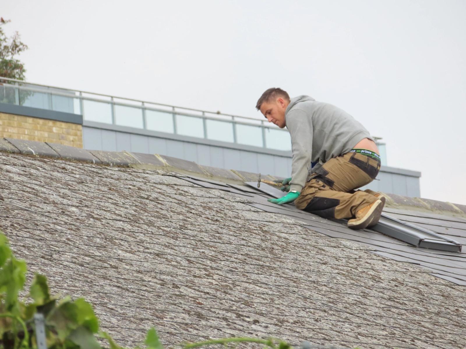 Roofing worker installing shingles on a residential roof