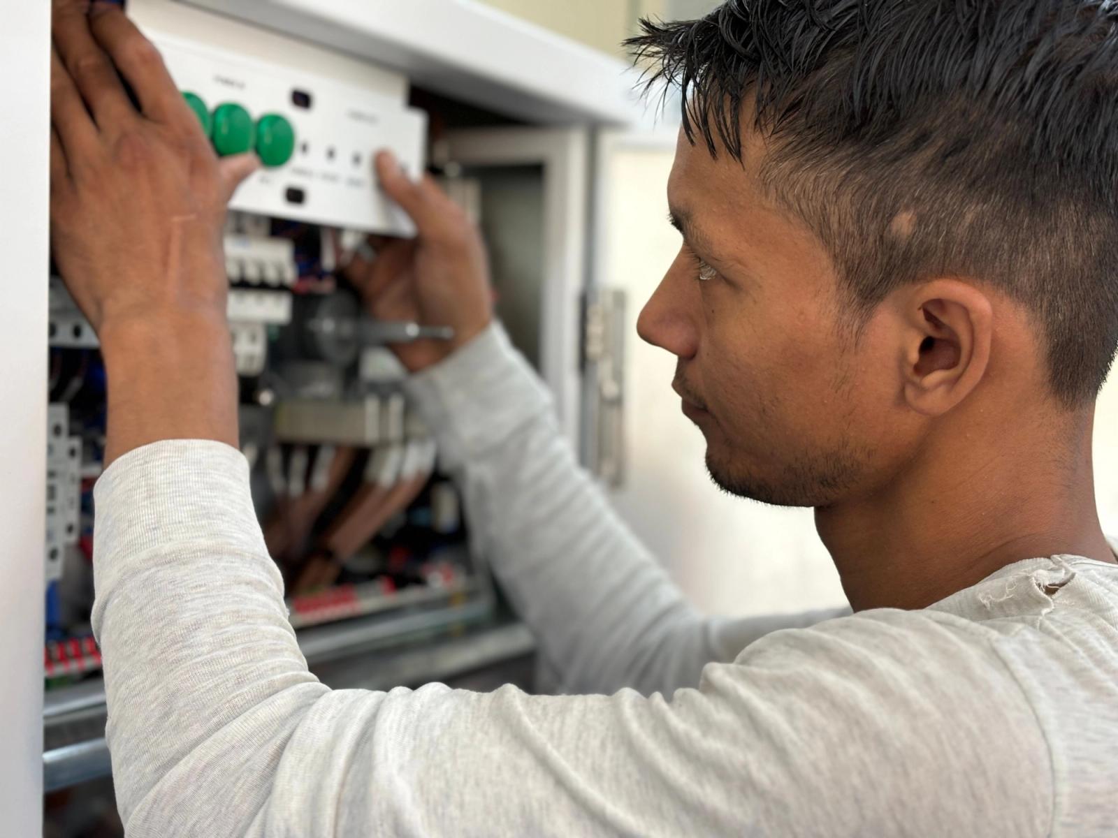 Electrician adjusting breakers inside an open electrical panel