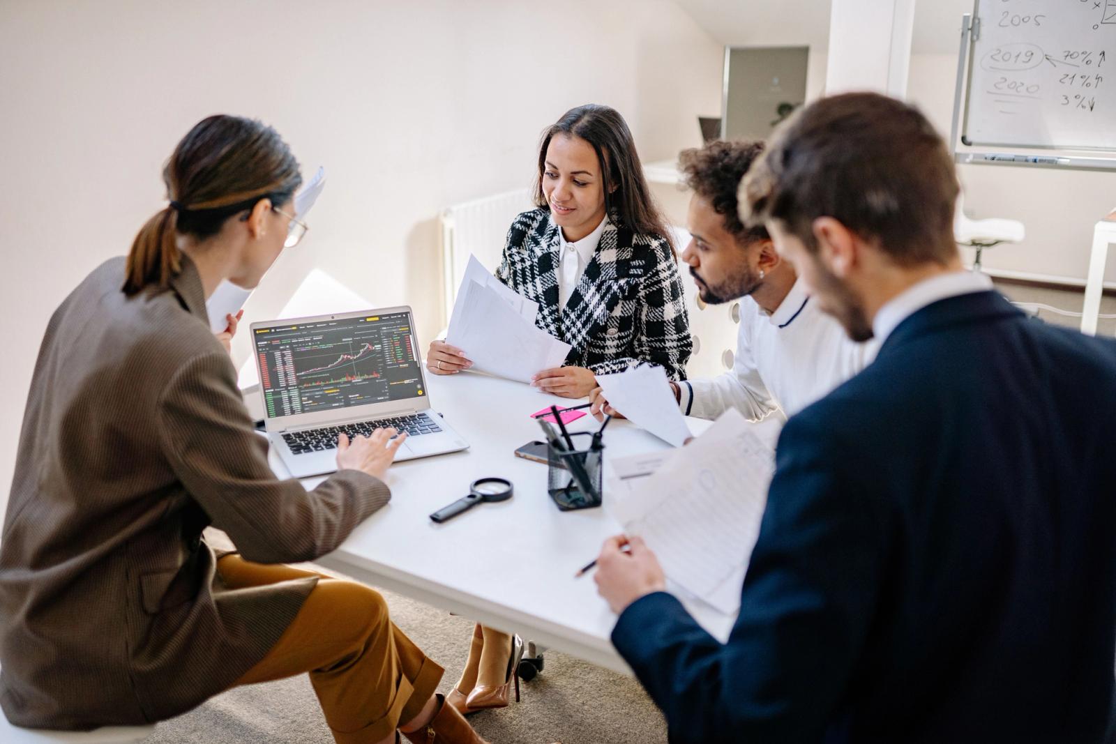 Two office professionals reviewing printed graphs at a table
