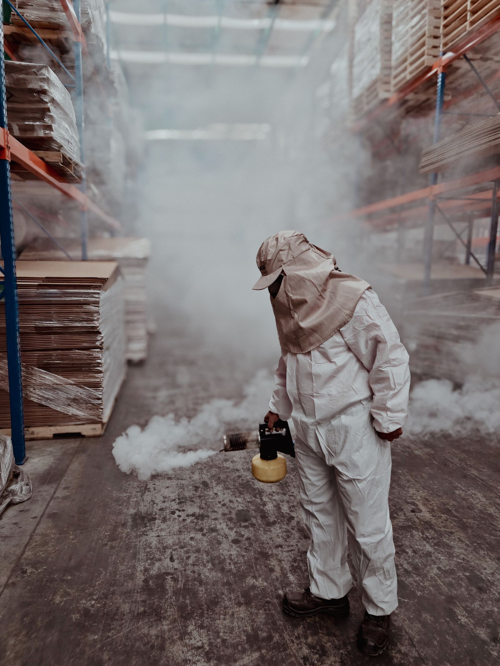 Pest control professional using fumigation equipment in a warehouse