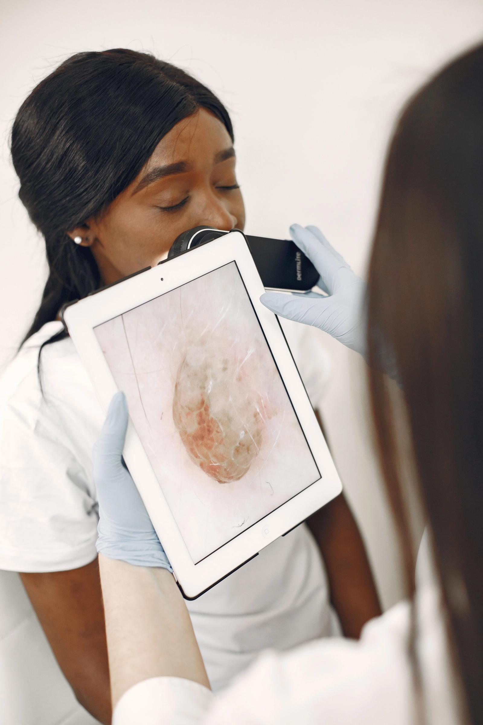 Dermatologist examining a patient's skin with a digital device in a clinic