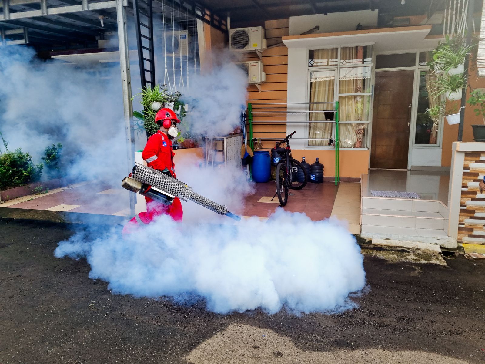 Pest control specialist operating a smoke machine outside a house