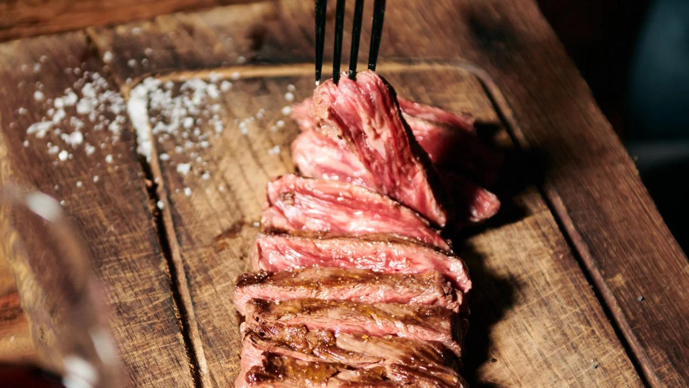 Aged ribeye fresh off the grill and sliced on a board at Carnal Steakhouse, meat restaurant in Eixample, Barcelona