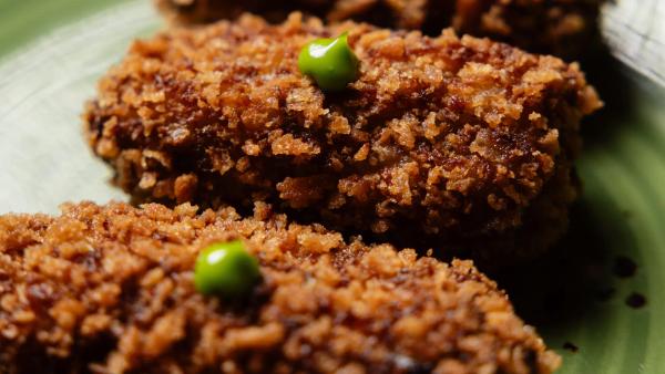 Croquetas de carrillera Black Angus recién fritas partidas por la mitad mostrando el interior cremoso, aperitivo de Carnal Barcelona
