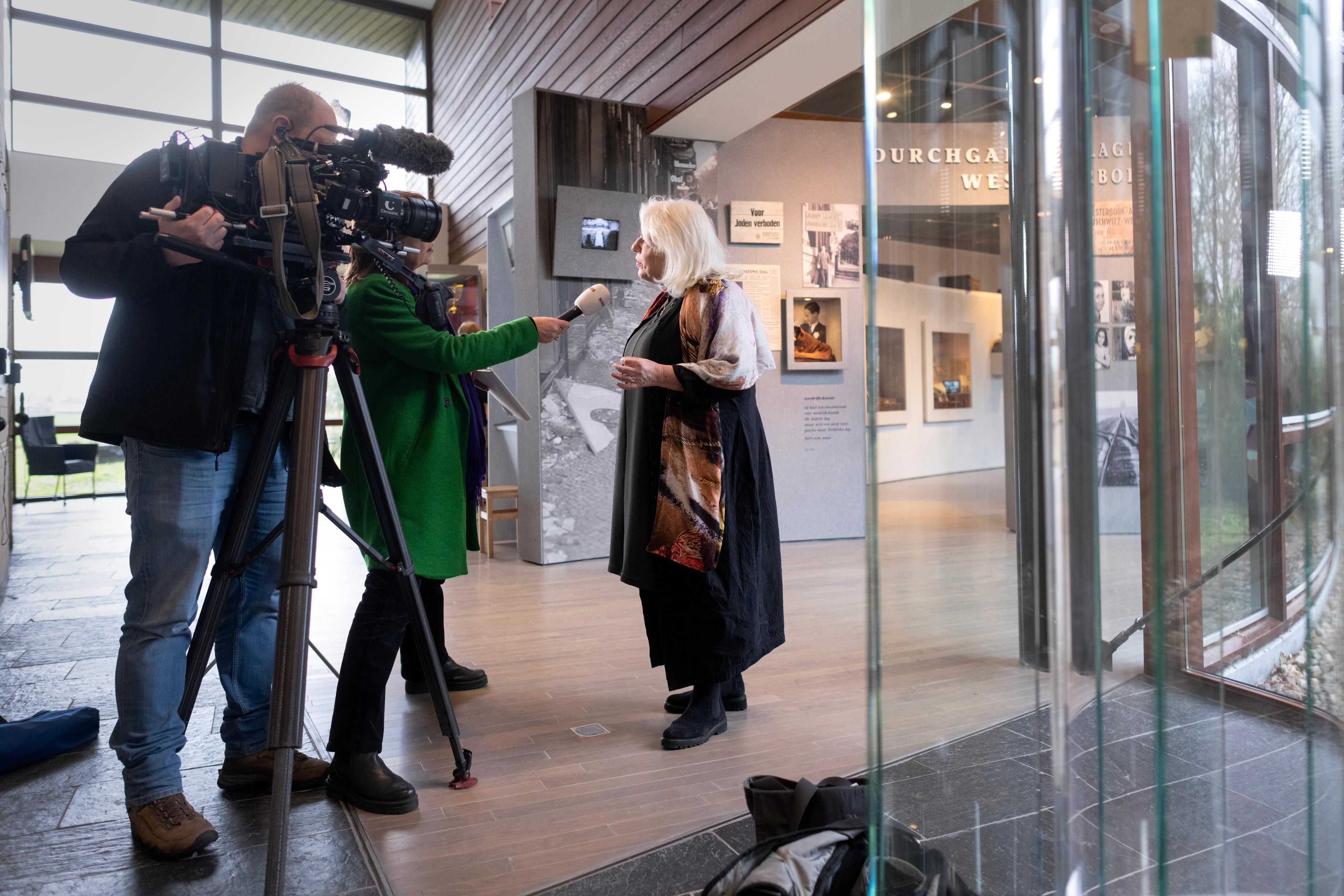 Directeur bertien minco wordt geïnterviewd in het museum van Herinneringscentrum Kamp Westerbork door een vrouw met microfoon en man met camera op statief