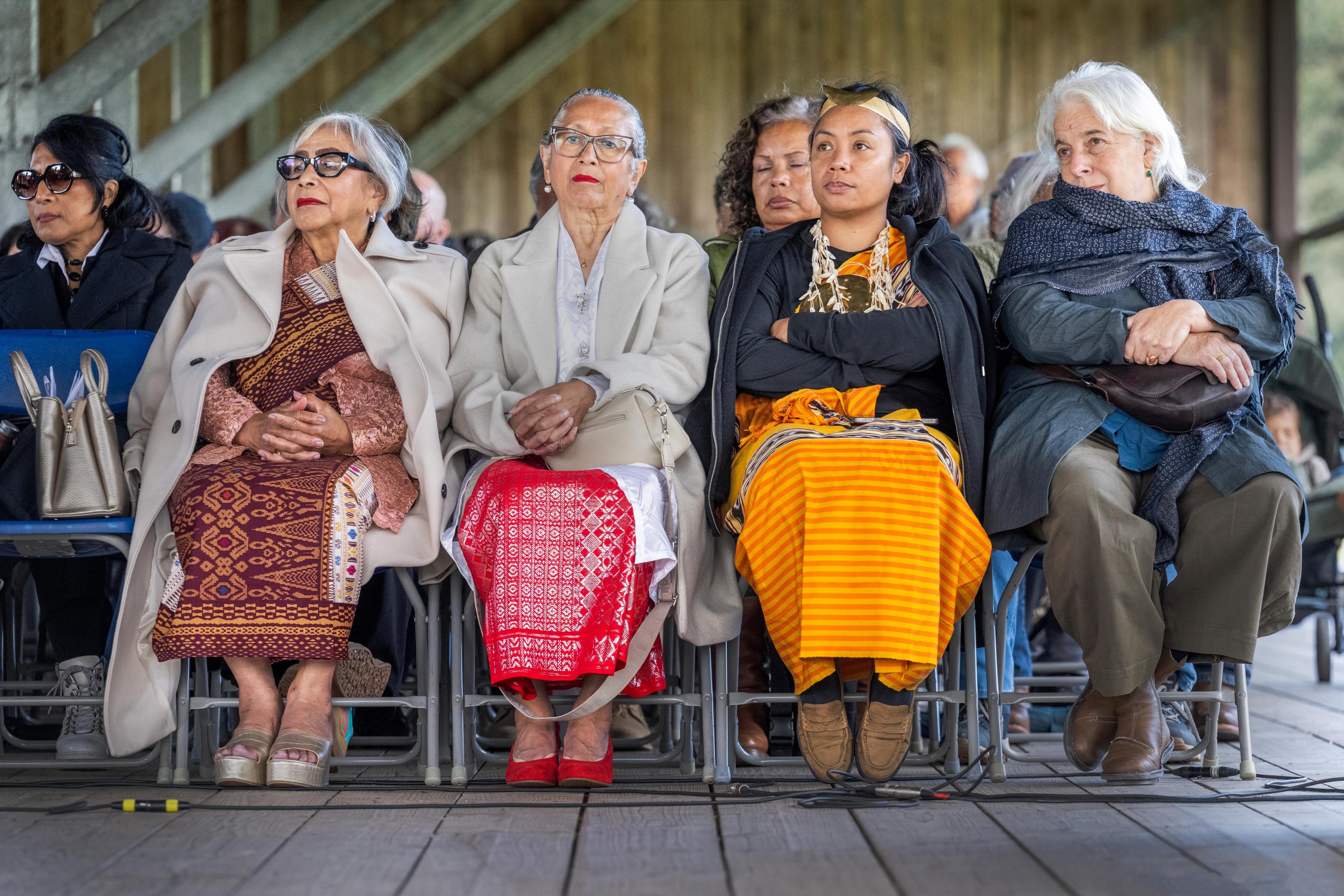 Drie Molukse vrouwen zitten op de voorste rij in het publiek naast directeur Bertien Minco tijdens de herdenking van 75 jaar Molukkers in Nederland