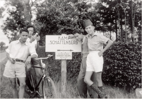 Zwart-wit collectiefoto van vier Molukse jongens die poseren bij een bord met daarop 'Kamp Schattenberg'