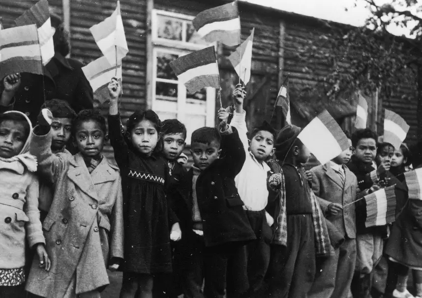 Historical photograph of children at the former Schattenberg residential home. The children are standing in a row, waving little flags in the air