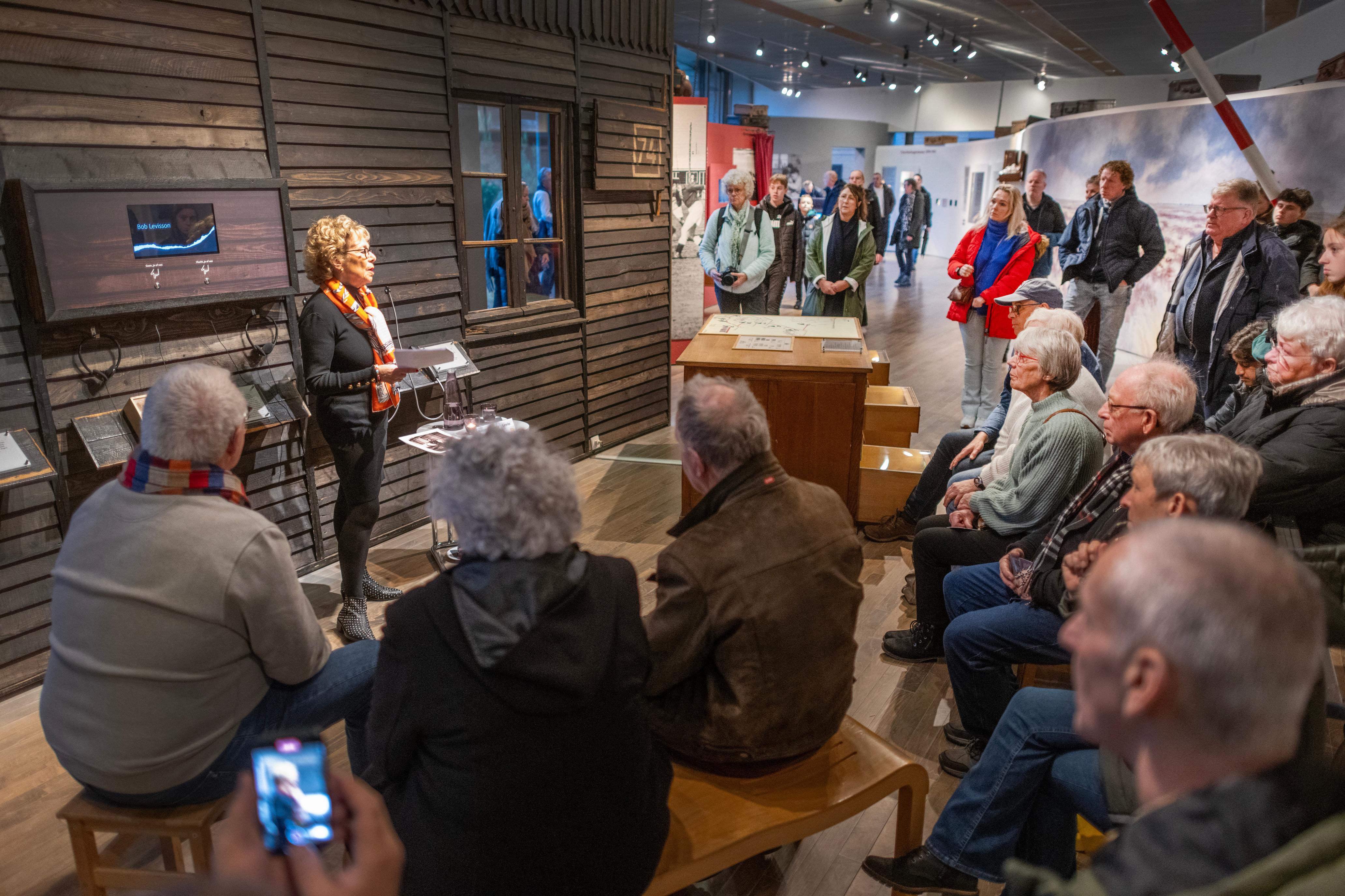 Vrouw vertelt verhaal aan groep bezoekers in het museum van Herinneringscentrum Kamp Westerbork