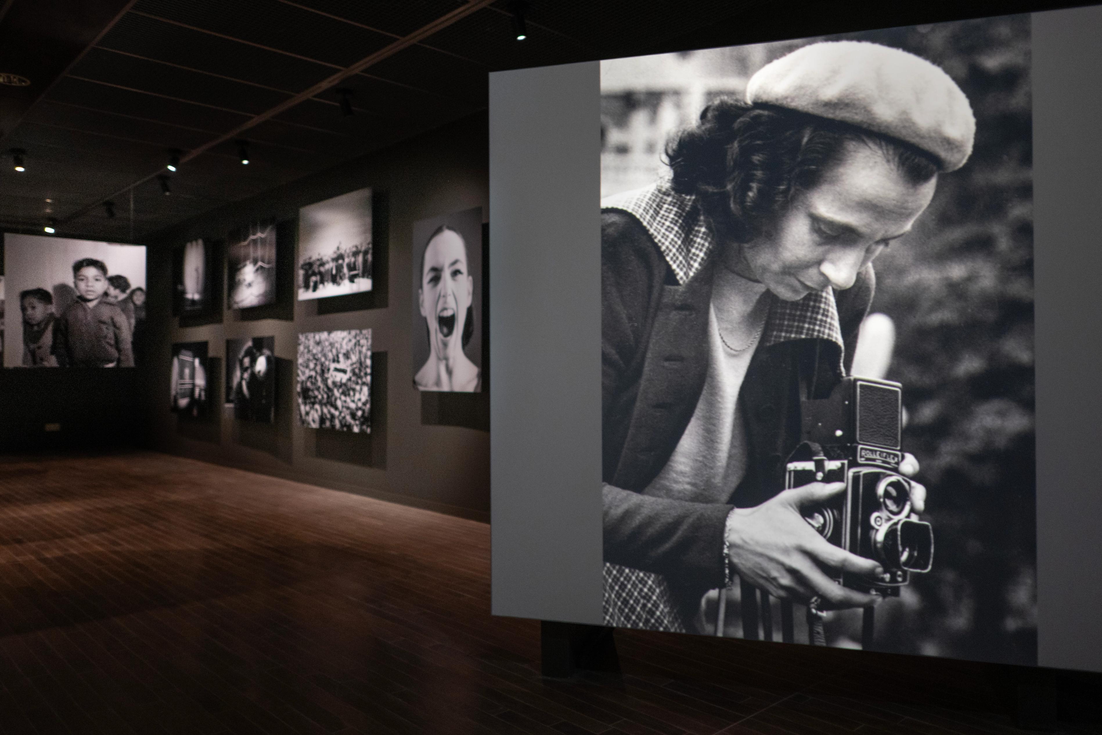 Oude zwart-wit foto in een tentoonstelling over Maria Austria, waarop Maria Austria te zien is terwijl ze kijkt door een oude fotocamera