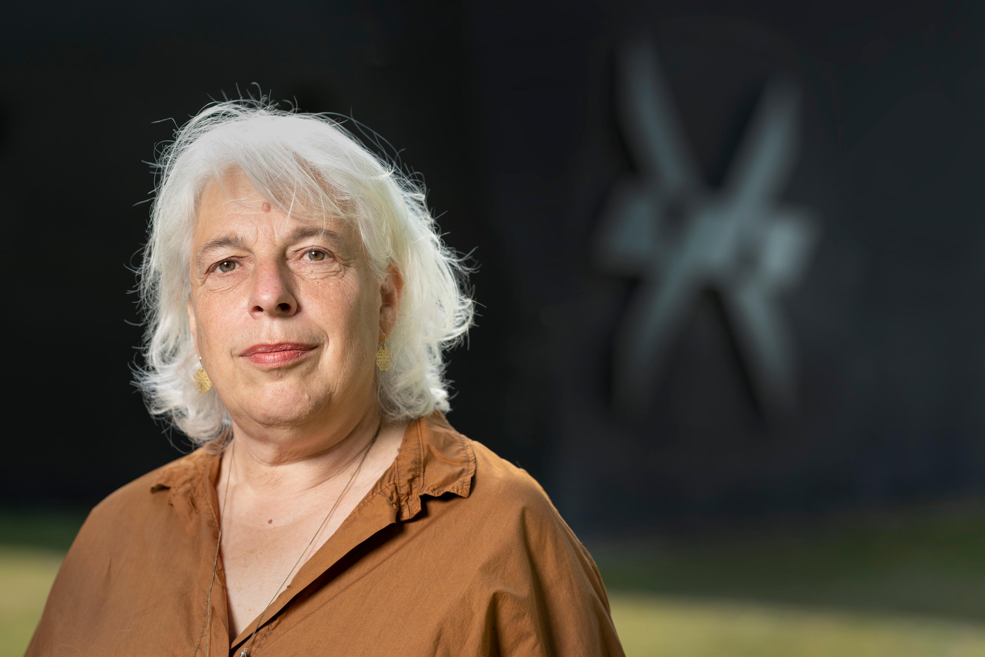 Directeur Bertien Minco van Herinneringscentrum Kamp Westerbork voor het Herinneringscentrum met het logo op de achtergrond