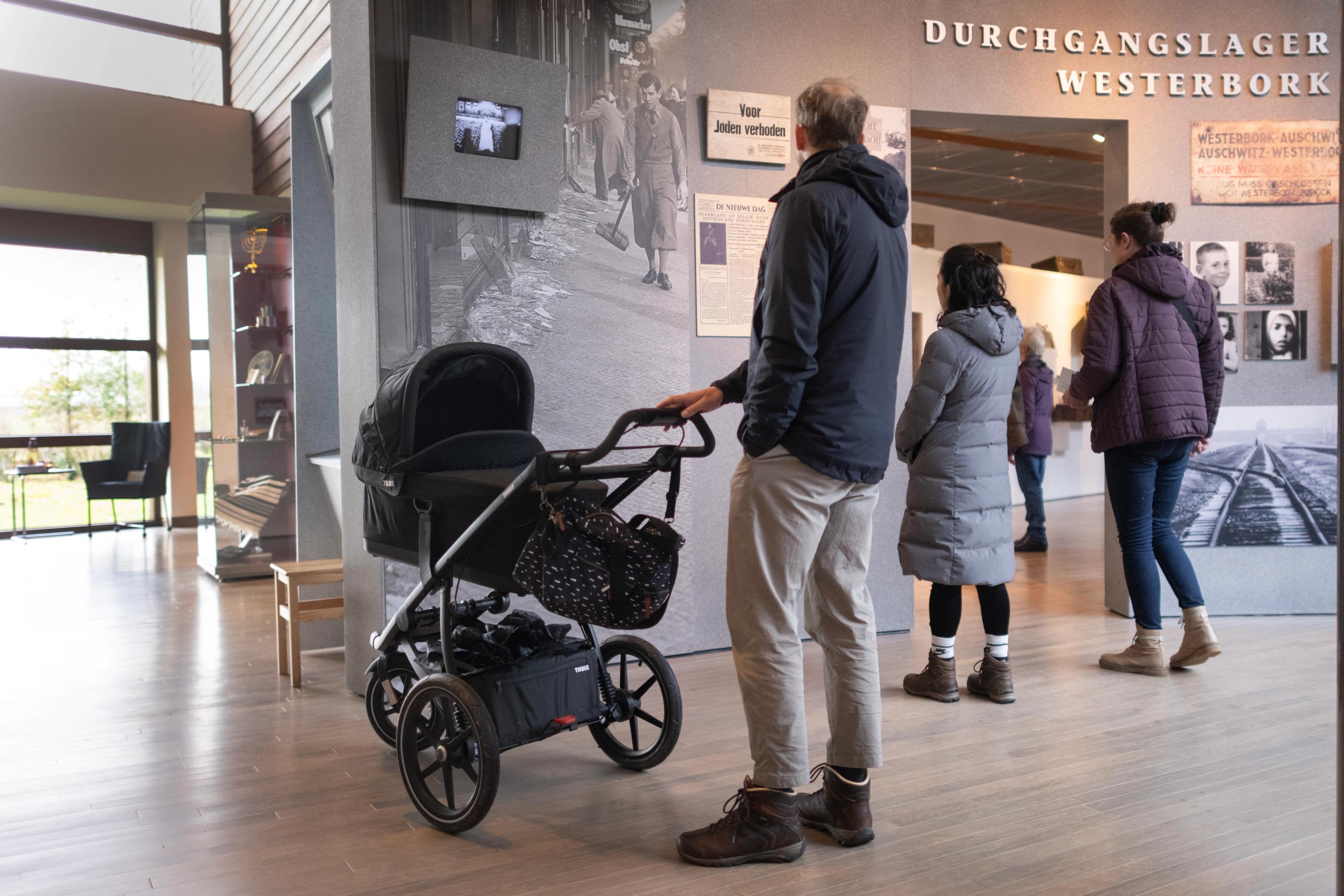 Man met kinderwagen kijkt naar de ingang van de vaste tentoonstelling in het museum van Herinneringscentrum Kamp Westerbork