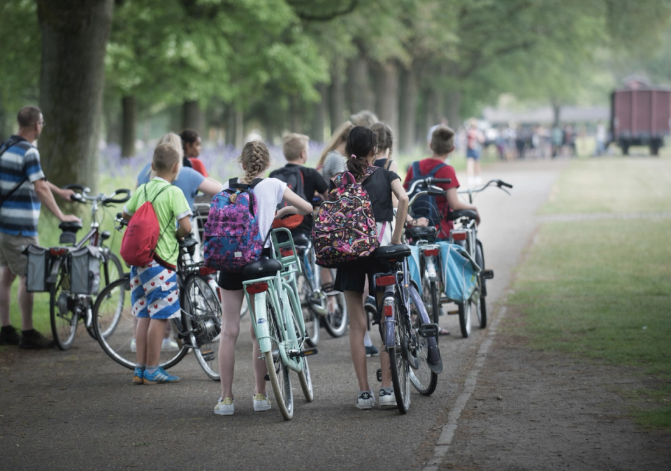 A group of children are waiting next to their bikes at the entrance to the former Westerbork camp site