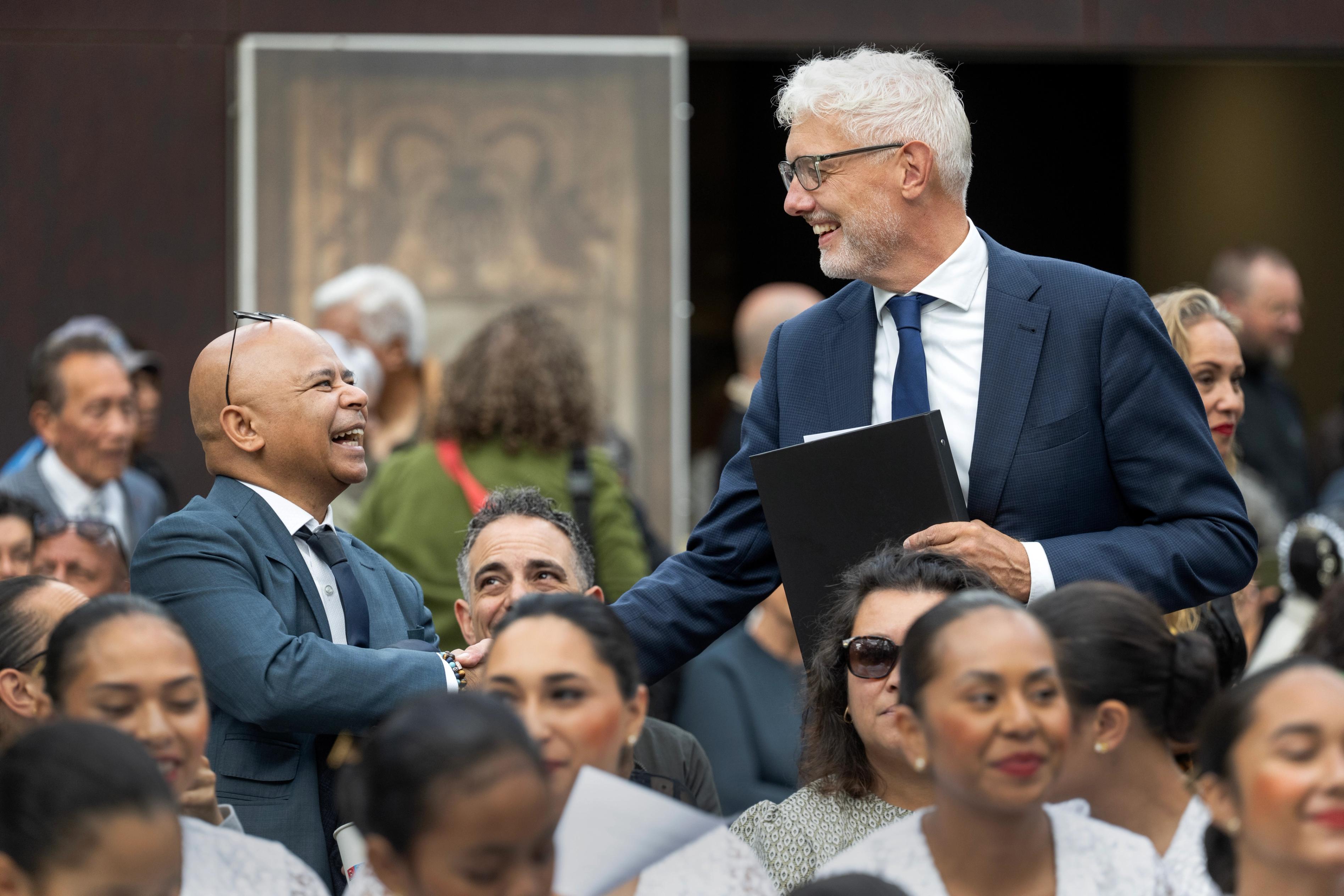 Twee mannen schudden elkaar de hand tijdens de herdenking van 75 jaar Molukkers in Nederland