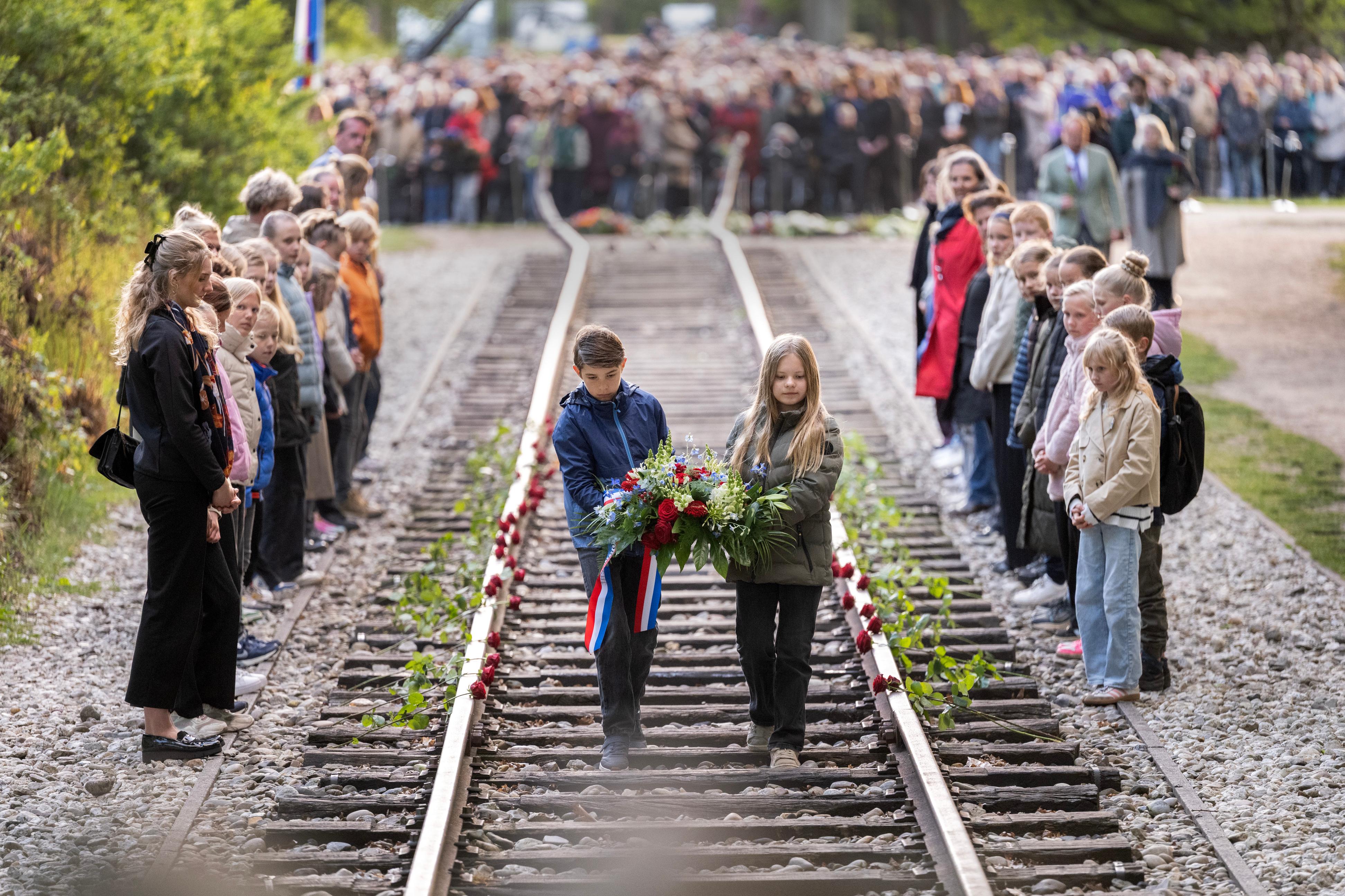Kinderen lopen over de treinrails van het Nationaal Monument bij kamp Westerbork om een bloemenkrans te leggen tijdens de Nationale Dodenherdenking op 4 mei
