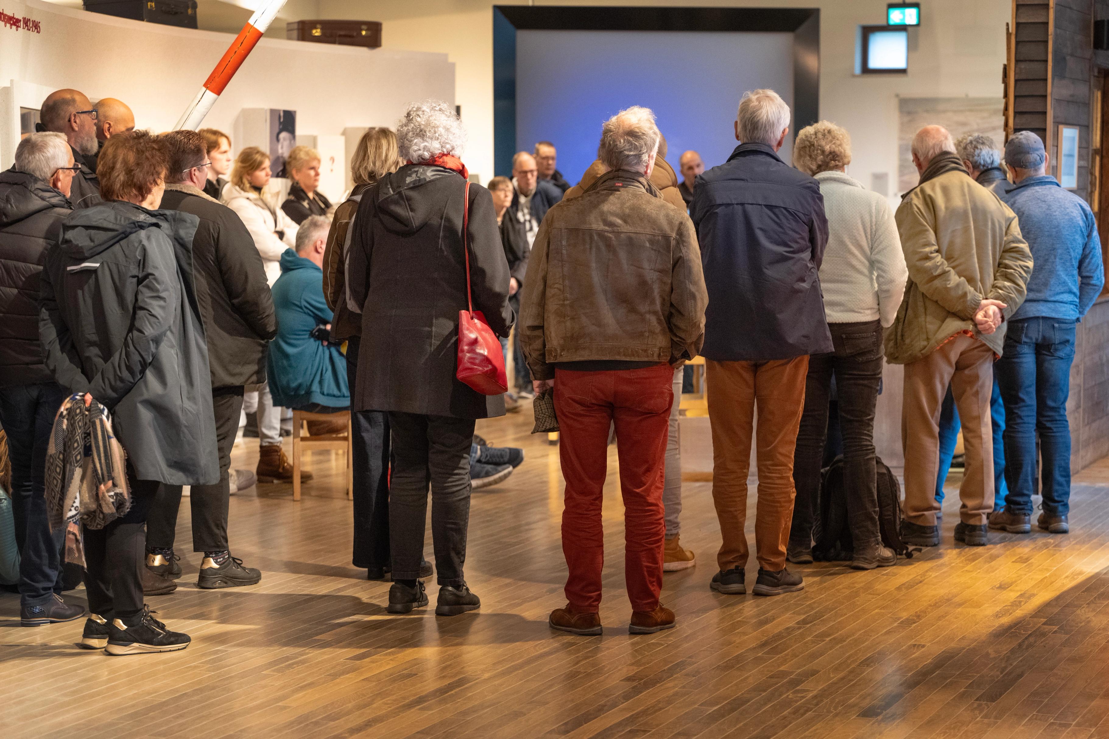 Bezoekers in het museum van Herinneringscentrum Kamp Westerbork kijken naar een spreker (ooggetuige)