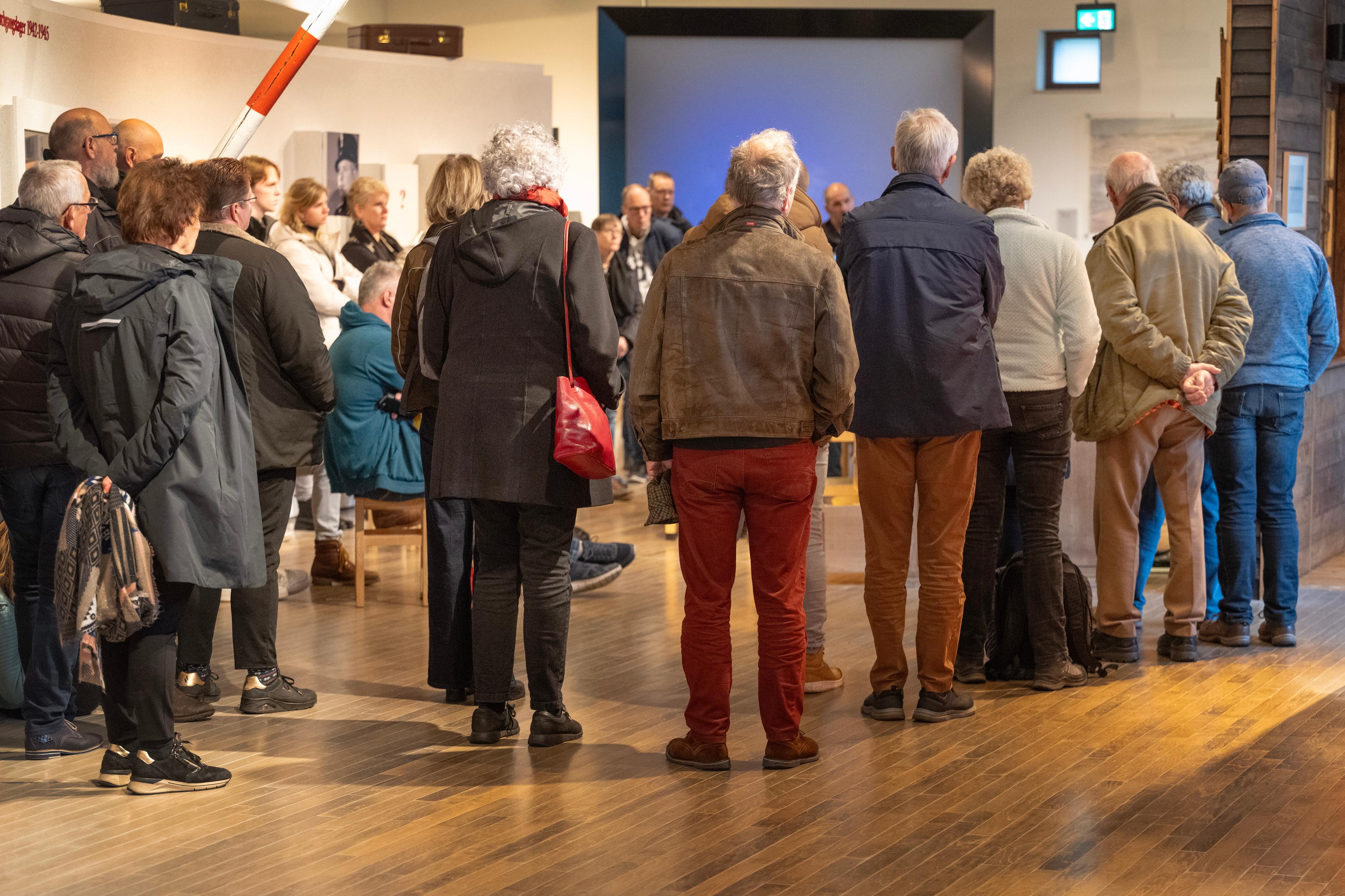 Bezoekers in het museum van Herinneringscentrum Kamp Westerbork kijken naar een spreker (ooggetuige)