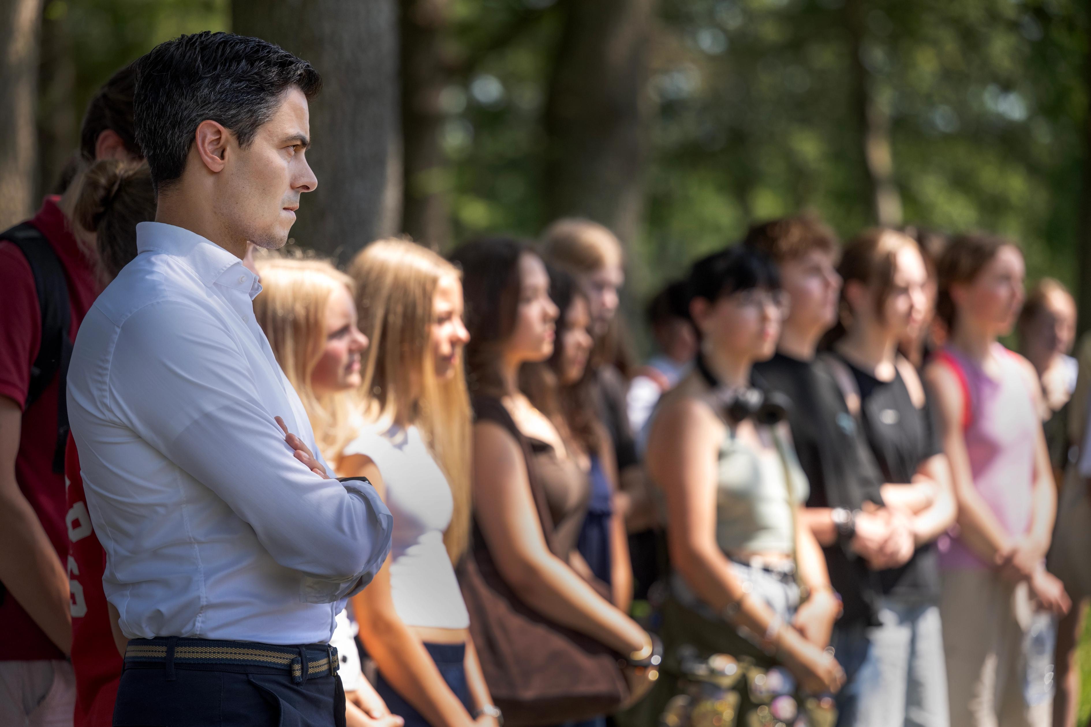 Minister-president Rob Jetten luistert aandachtig naast een rij scholieren
