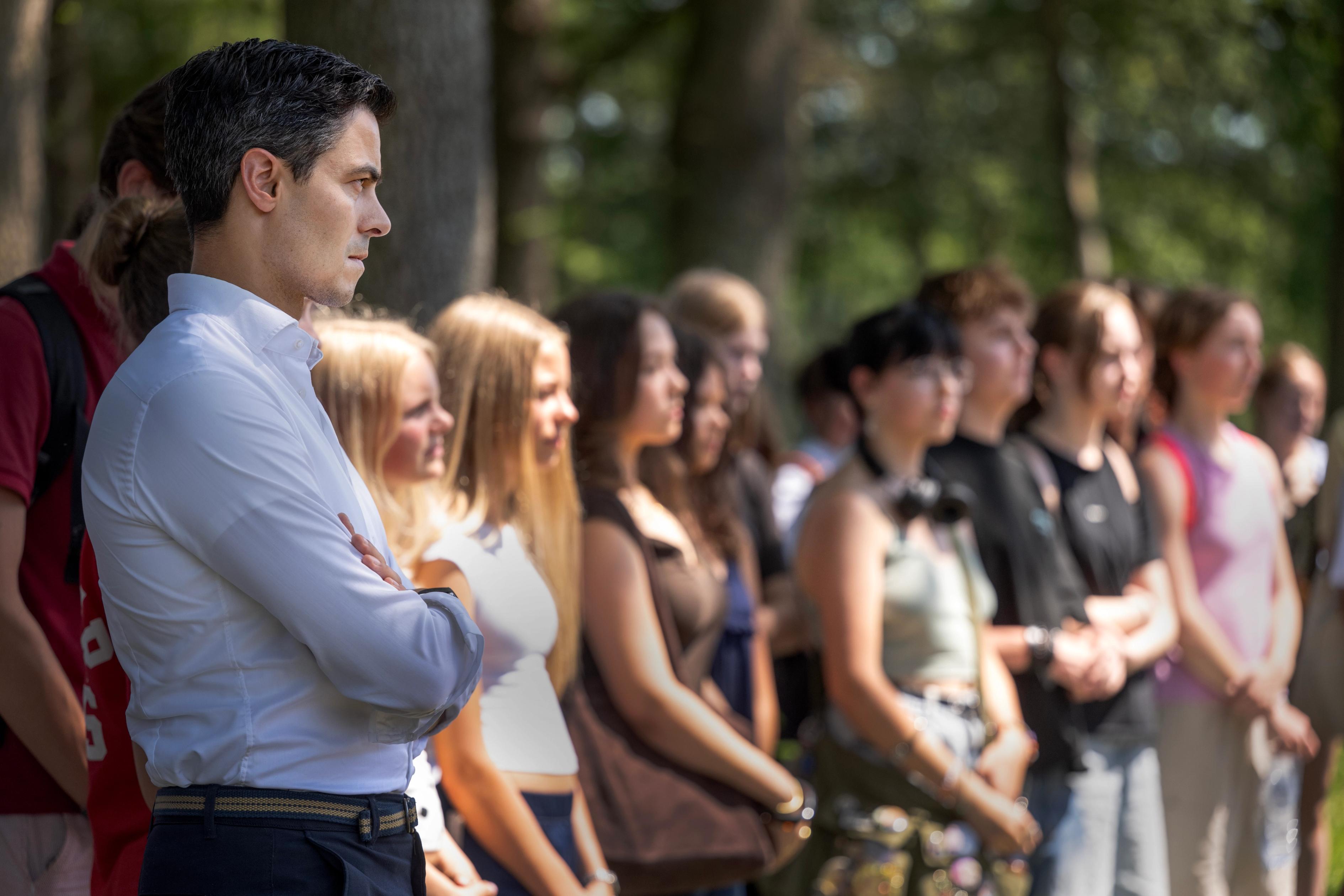 Minister-president Rob Jetten luistert aandachtig naast een rij scholieren