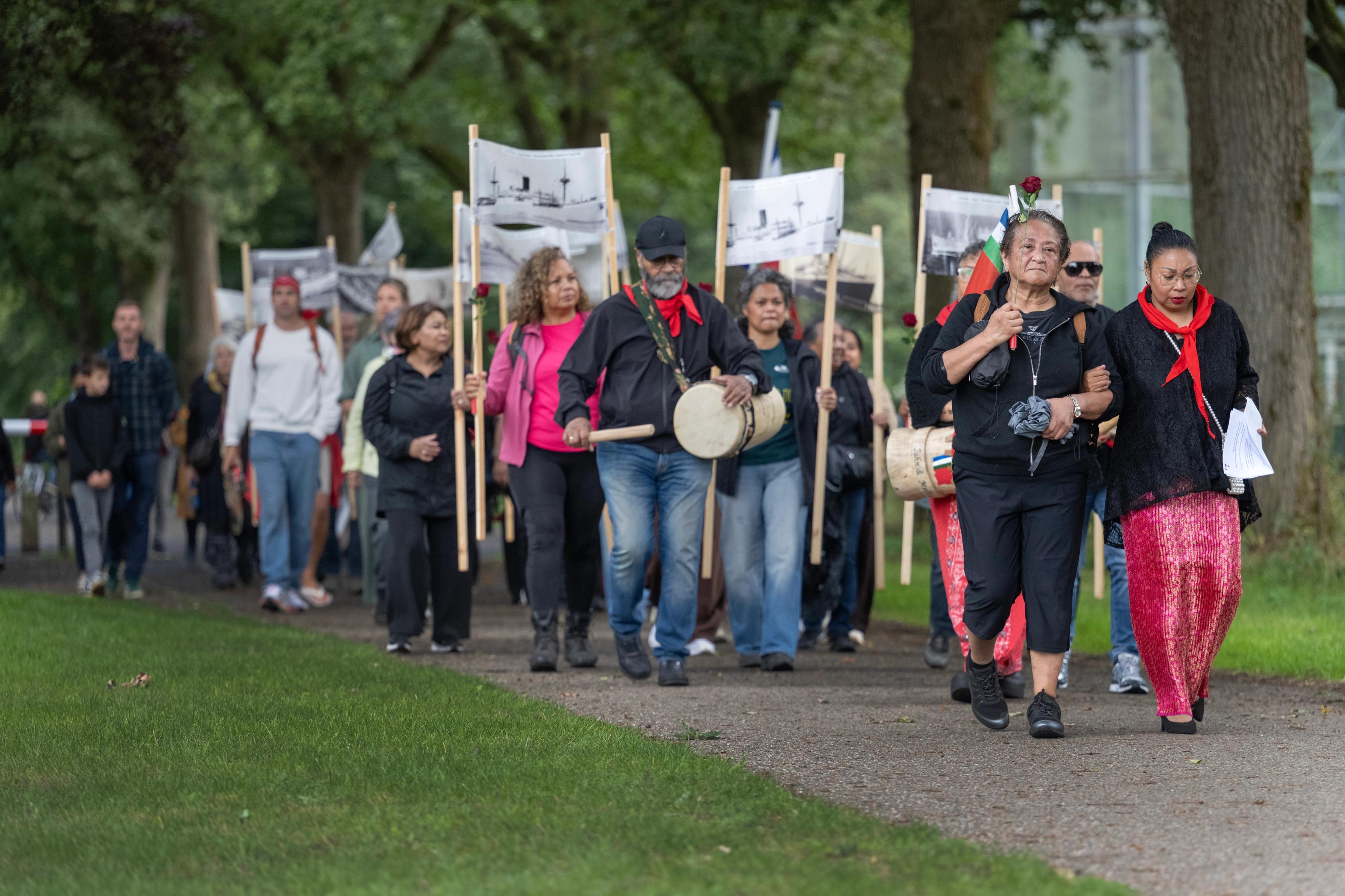 Een stoet mensen wandelt op het voormalig kampterrein van kamp Westerbork voor de herdenking van de aankomst van Molukkers in voormalig kamp Schattenberg