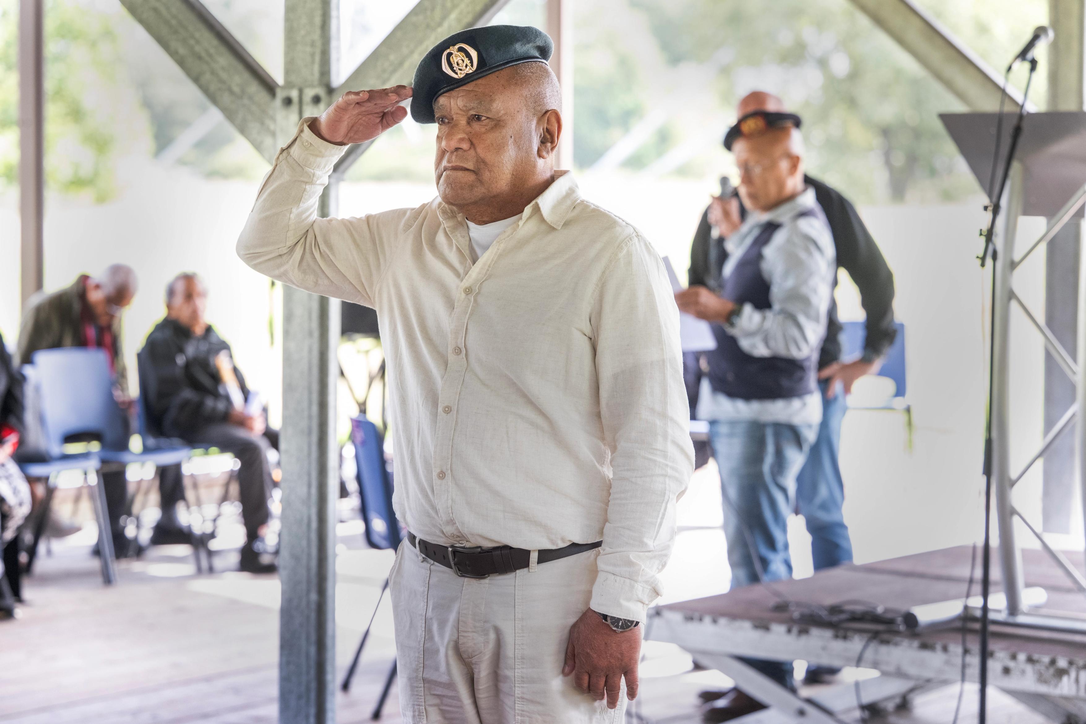 Molukse man met militaire baret op saluteert tijdens de herdenking van 75 jaar Molukkers in Nederland