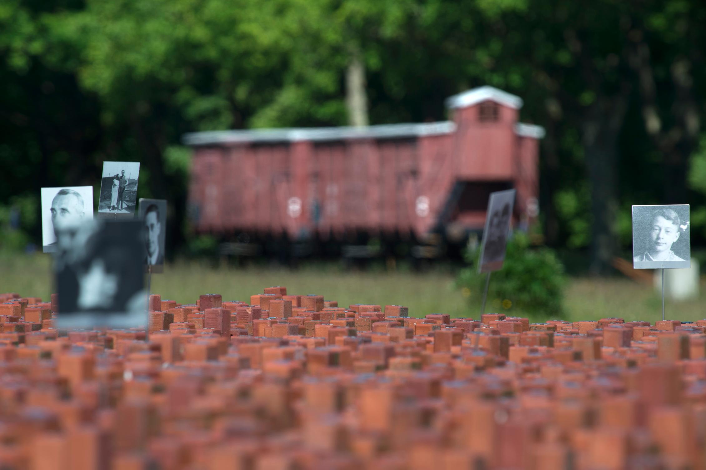 Close-up van de 102.000 Stenen monument met op de achtergrond de wagon van kamp Westerbork