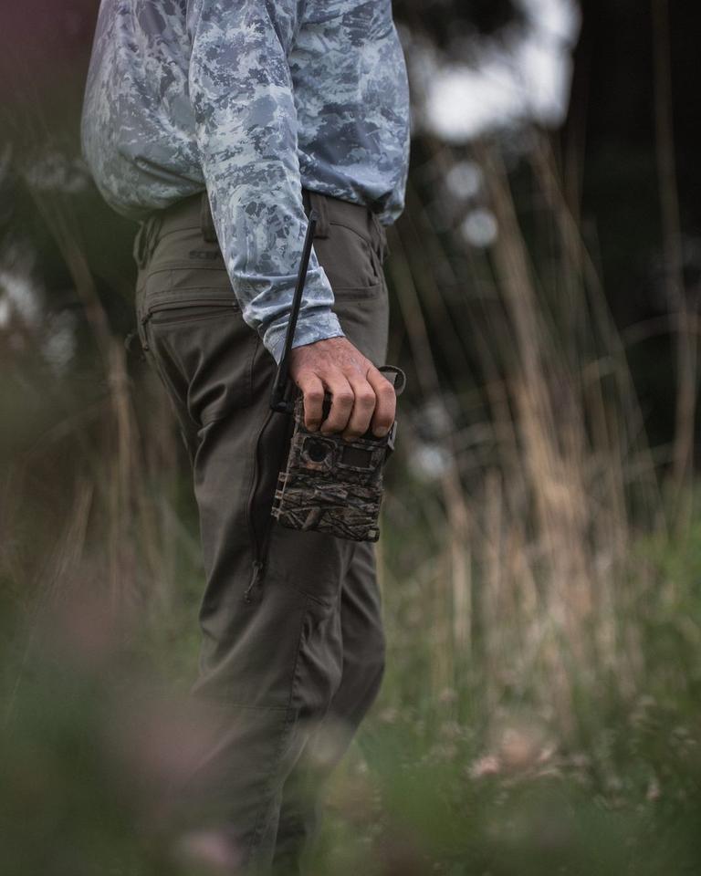 Researcher carrying a Y2 trail camera through a field