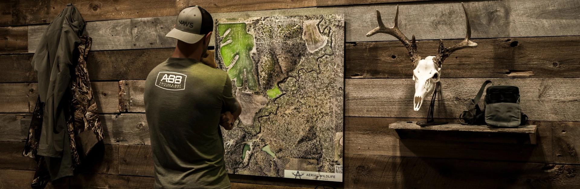 Hunter reviewing an aerial property map beside hunting gear