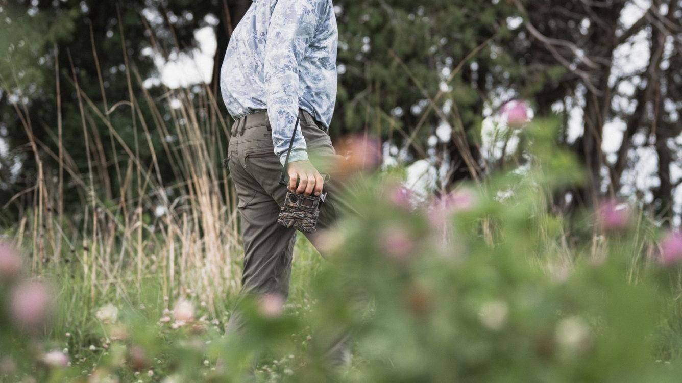 Hunter carrying a Y2 trail camera through a summer field