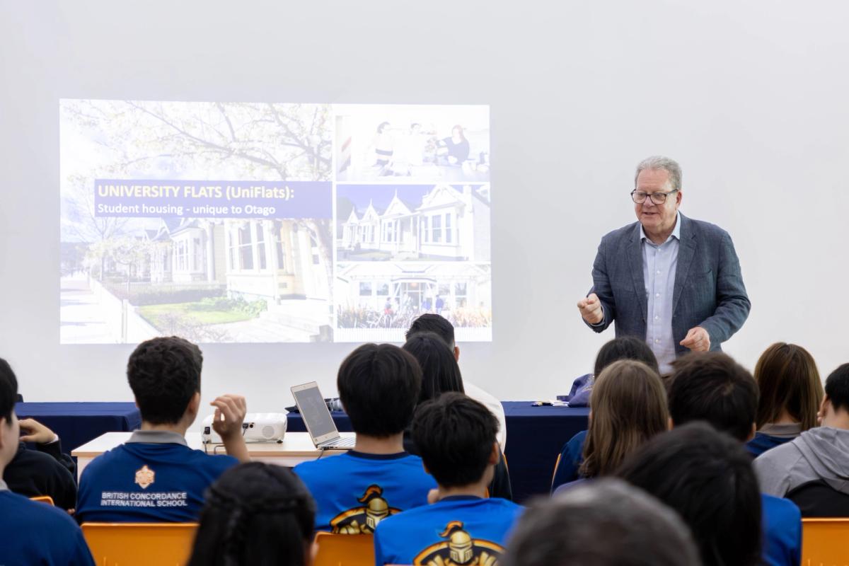 BCIS students in school polo shirts sit in the front row as Mr Garry Chronican presents a slide about Otago's UniFlats student housing.