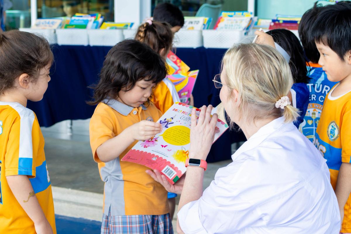 A staff member looks through a second-hand craft book with a young pupil at the book fair's second-hand table.
