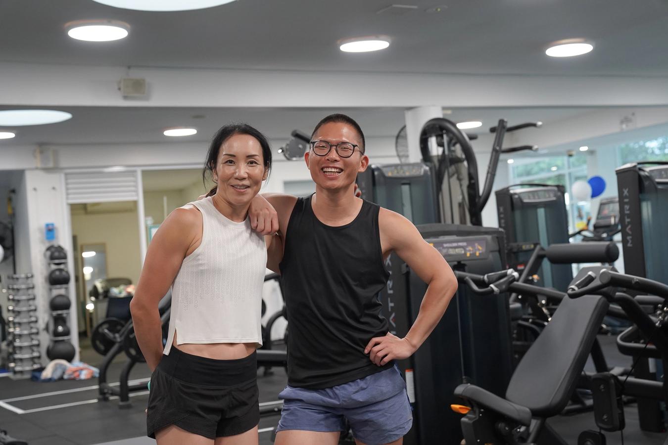 Two people in active wear smiling in the gym