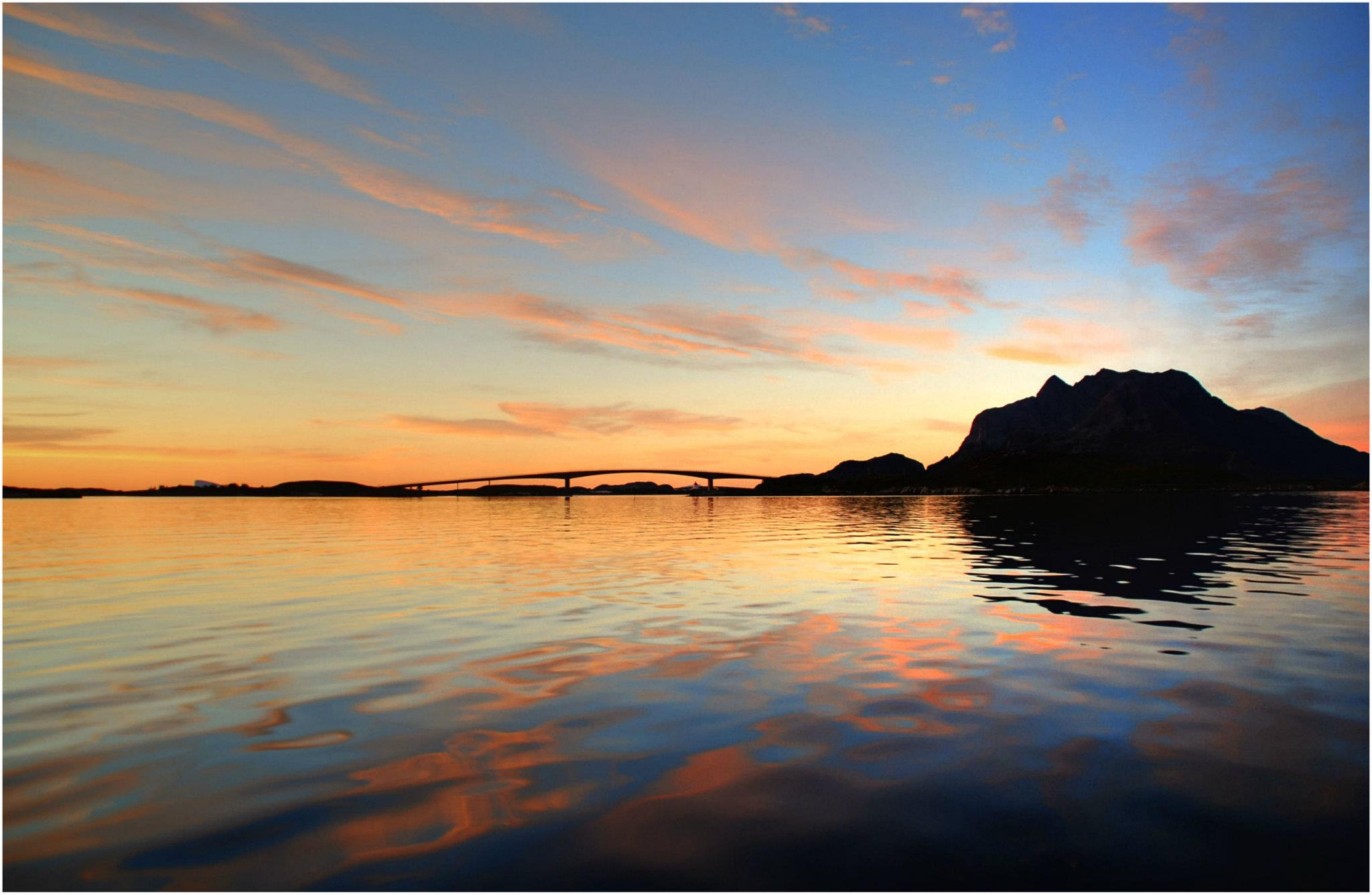 Herøybrua speiler seg i sjøen i solnedgang