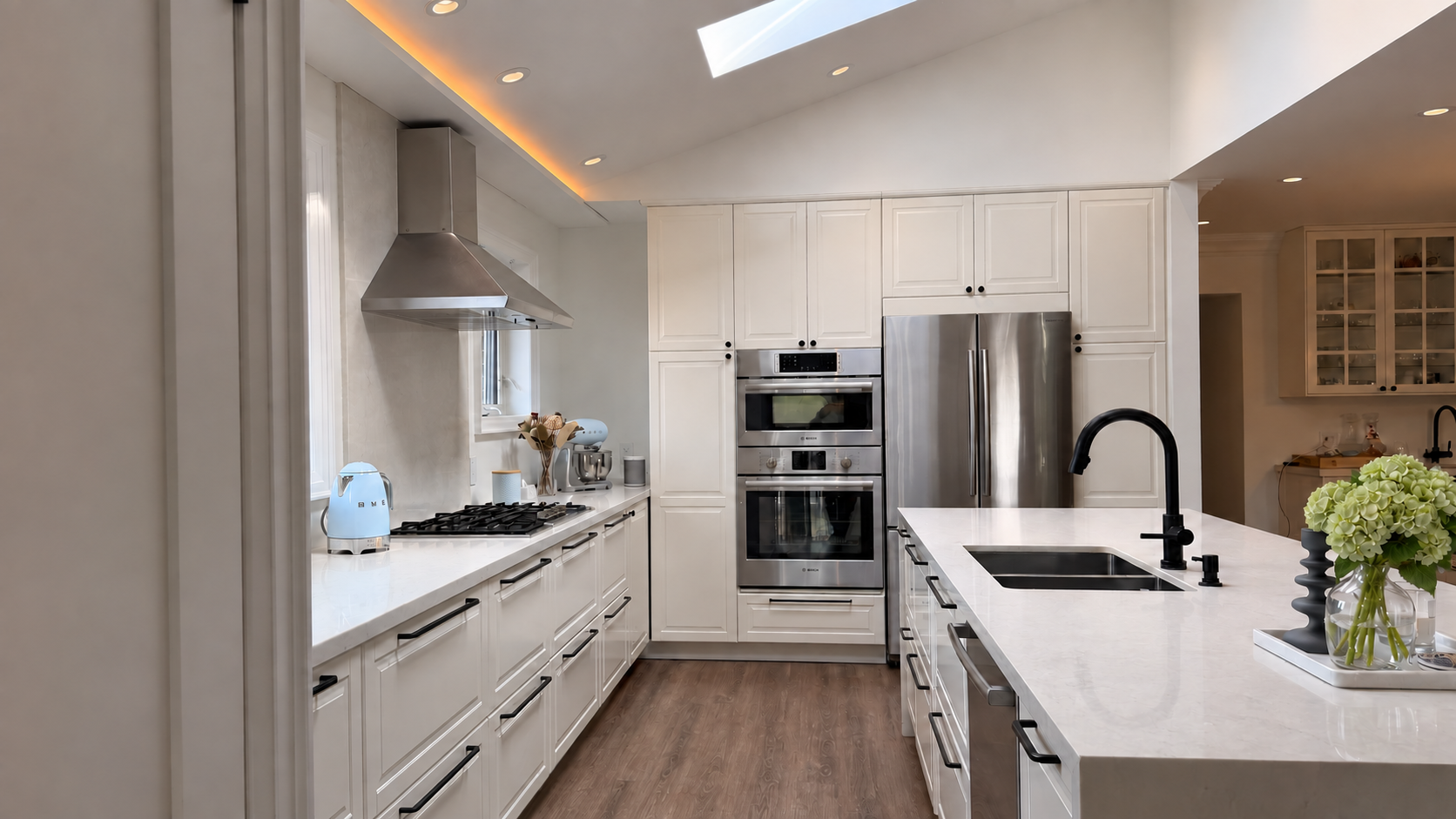 Modern kitchen fully renovated with a full size island, waterfall marble counter tops, marble back splash, appliance wall and skylights to brighten up the space.