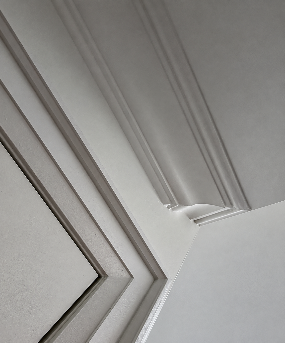 White kitchen cabinetry and crown moulding with recessed ceiling lights